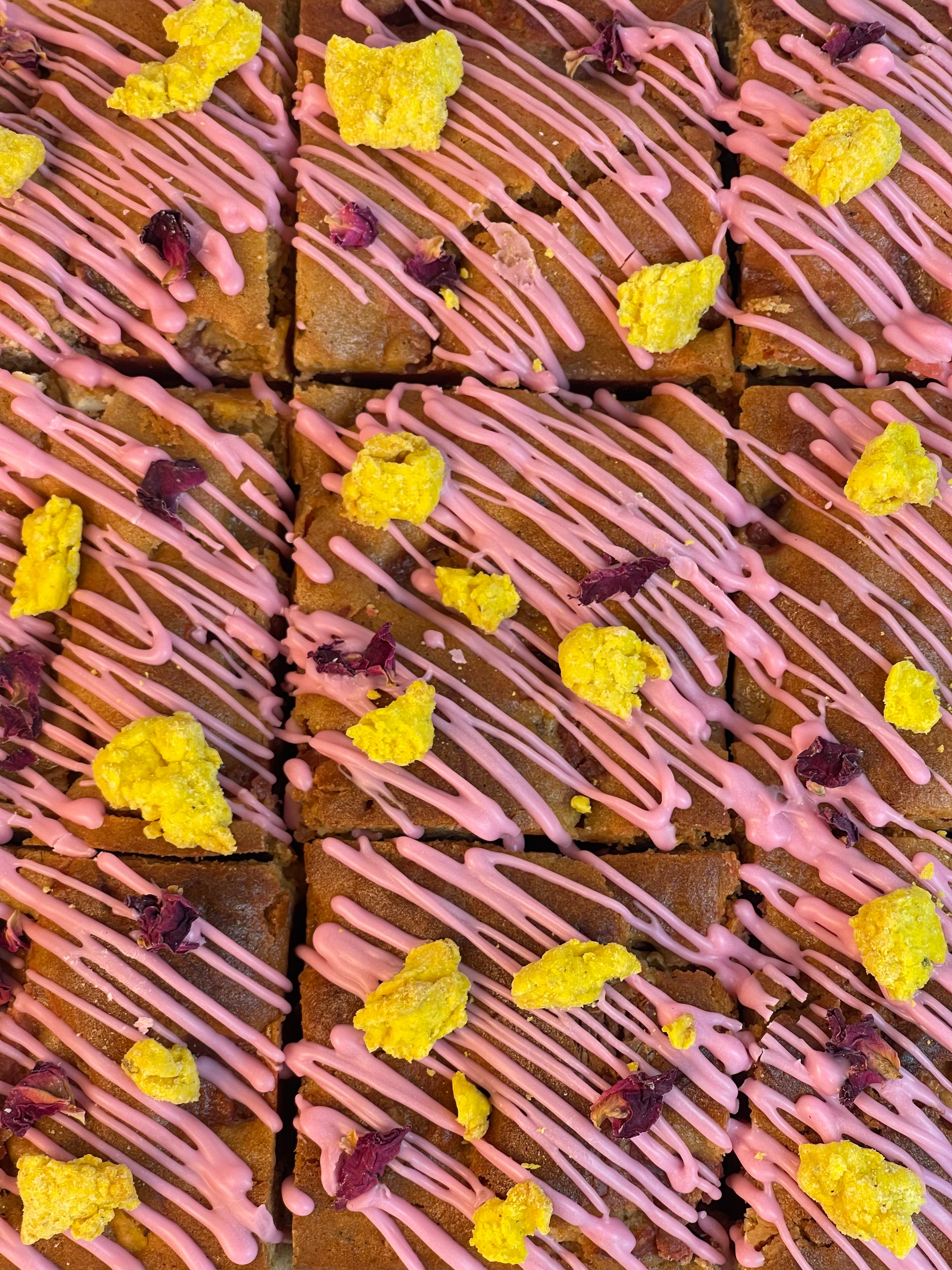 Brownies with pink drizzle and yellow and purple decorations