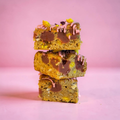 Brownies with pink drizzle and yellow and purple decorations