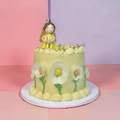Decorative cake with a figurine and floral designs on a pink and purple gradient background
