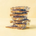 Stack of chocolate-covered toffee pieces on a light yellow background
