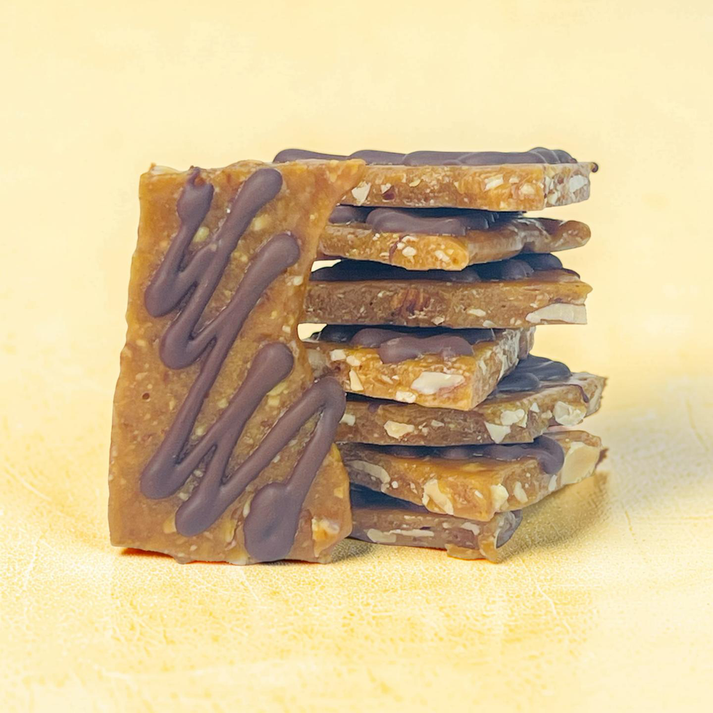 Stack of chocolate-dipped toffee bars on a light yellow background