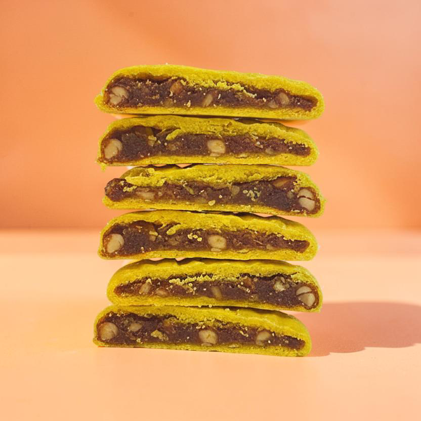 Stack of green cookies with dark filling on a peach background