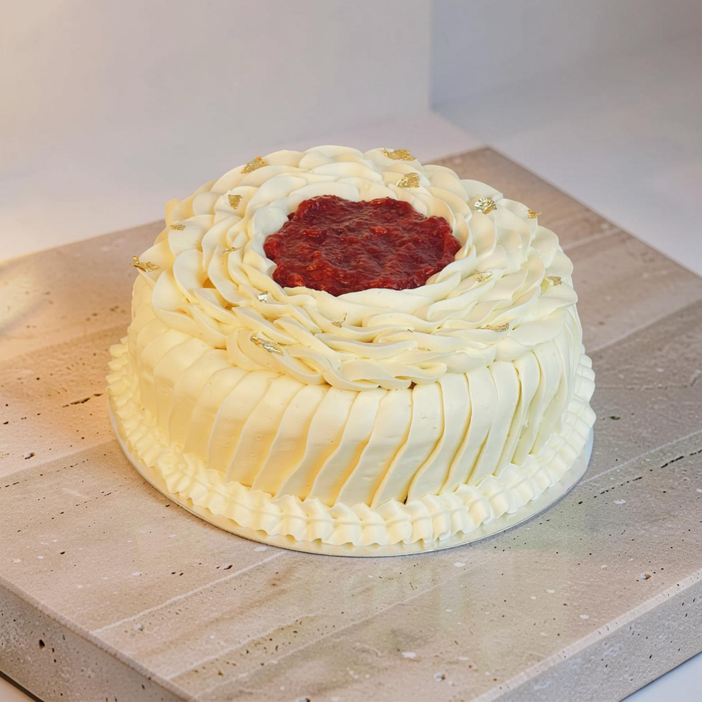 Decorative cake with white frosting and a red center on a wooden surface