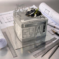 Decorative box with architectural design on a table with blueprints and tools