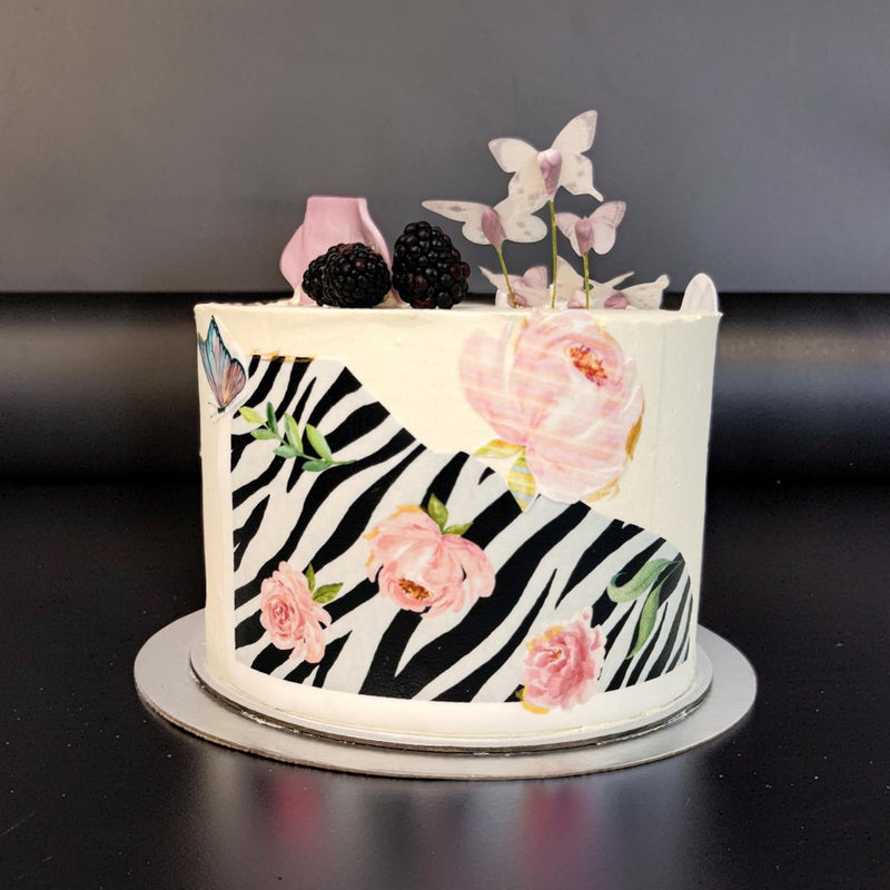 Cake with zebra pattern and floral decorations on a dark background